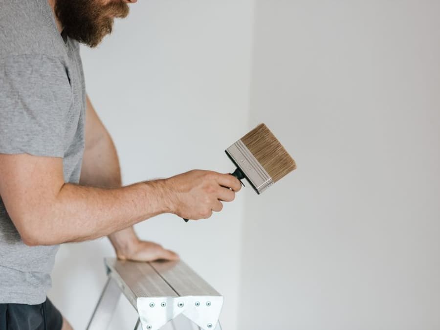Beispielfoto: Handwerker streicht mit einem Flächenstreicher eine weiße Wand